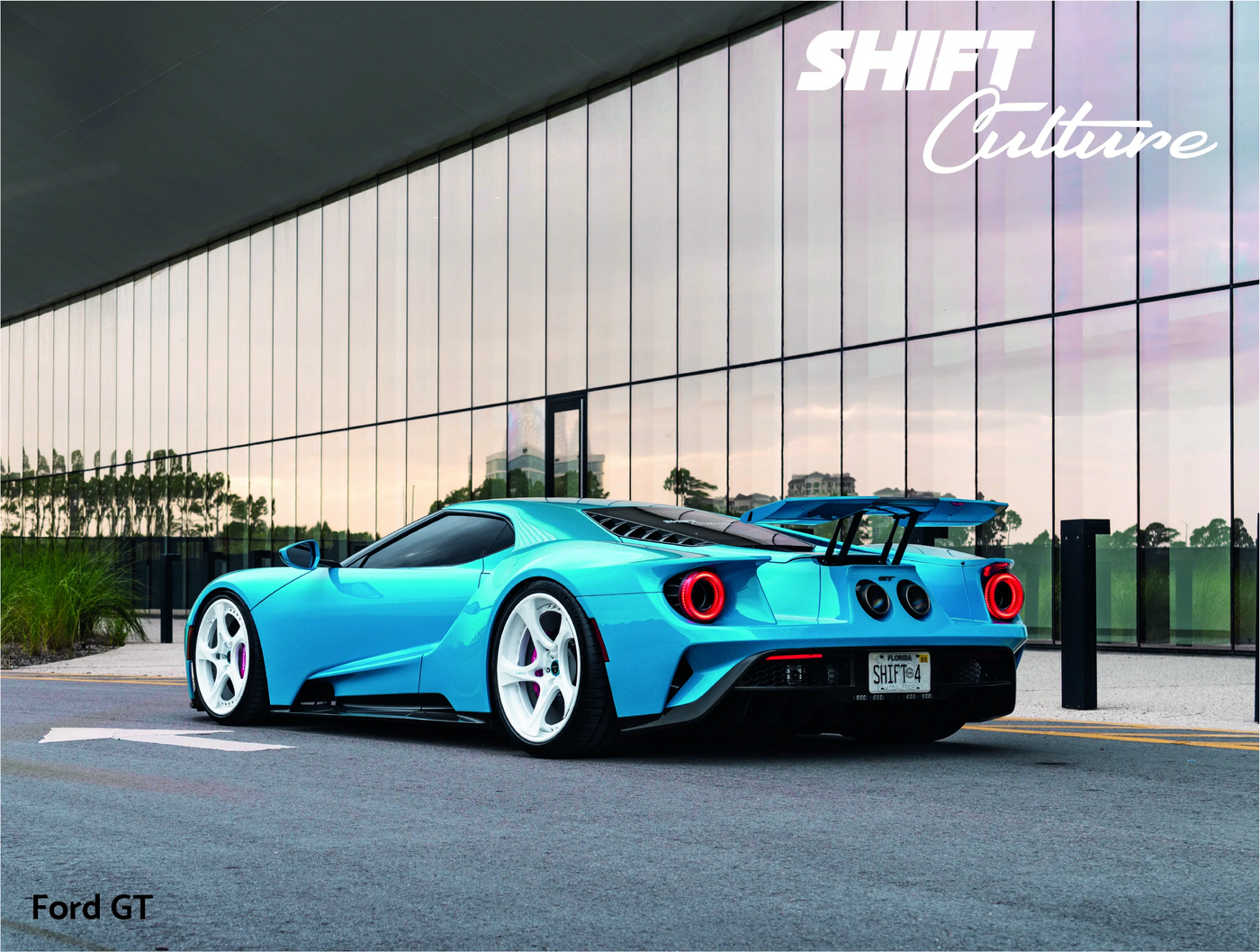 Blue Ford GT car parked on a street with a modern building in the background
